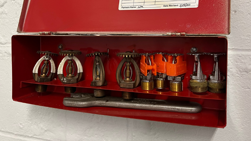 Spare fire sprinklers in a utility box on the wall